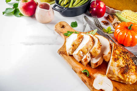 Thanksgiving holiday table with traditional festive food - turkey, pumpkin pie, pumpkins, green beans, cranberry sauce, corn, autumn apples, white marble table, top view copy space for textの写真素材