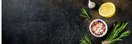 Cooking food ingredients background. Spices, garlic, herbs, olive oil. rusty black stone table. Copy space above bannerの写真素材