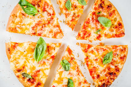 Homemade sliced cheesy classic italian pizza with ingredients and olive oil, white marble background...