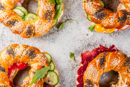 Variety of homemade bagels sandwiches with sesame and poppy seeds, cream cheese,  ham, radish,...