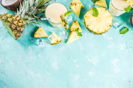 Refreshing summer drink, homemade pina colada cocktail, on a light blue background, with pieces of...