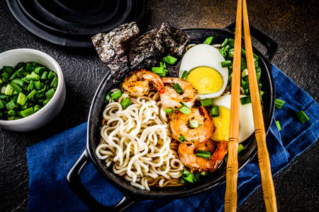 Traditional asian food, ramen soup with shrimp, noodles, spring onion, sliced eggs, mushrooms, on...