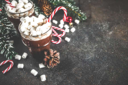 Peppermint hot chocolate with marshmallow and candy cane sweets in glass cups for Christmas holiday, dark rusty background toned copy spaceの写真素材