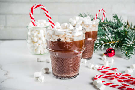 Peppermint hot chocolate with marshmallow and candy cane sweets in glass cups for Christmas holiday, white marble background copy spaceの写真素材