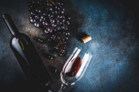Red wine bottle with glass and grapes, dark background copy space top view selective focusの写真素材