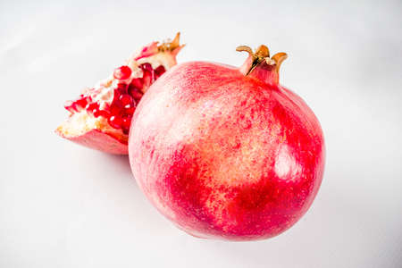 Fresh raw juicy whole and broken pomegranate on white background, top view flatlay creative layout
