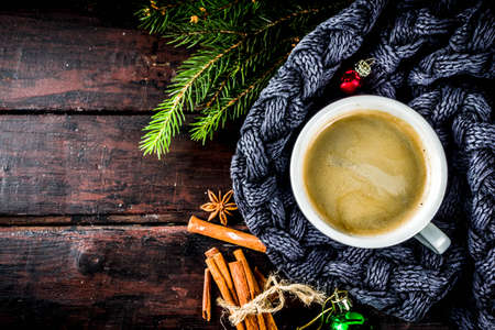 Spicy cappuccino coffee with for cold winter and autumn day. Xmas morning concept. Classic wooden background with christmas tree and decorations, copy space top viewの写真素材