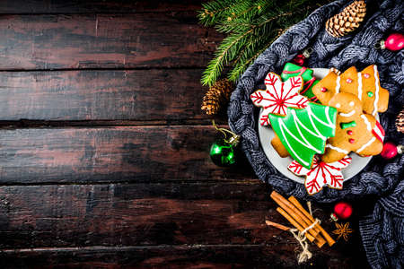 Traditional christmas sweet treats, colorful sugar glazed homemade gingerbread cookies with xmas tree, decoration, spices and coffee latte mud on classic wooden background copy space top viewの写真素材