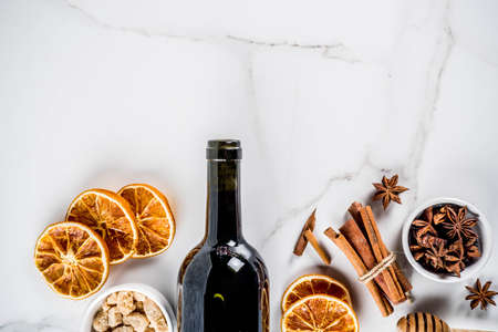 Ingredients for traditional autumn drink, mulled wine cocktail - red wine, stale oranges, cane sugar, honey, cinnamon, spices, anise, on white marble background, top view space for textの写真素材
