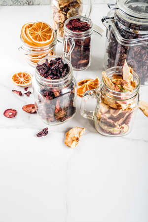 Home autumn harvest, dried fruits and berries in glass jars for canned preserves, strawberries, raspberries, apples, bananas, oranges, light concrete background, copy spaceの写真素材