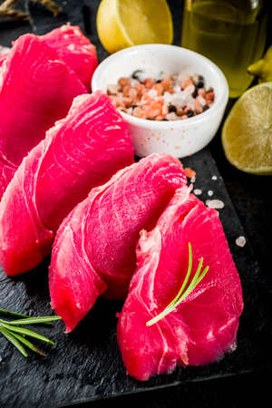 Fresh raw tuna fish steaks with ingredients for cooking, black stone background copy space top viewの写真素材