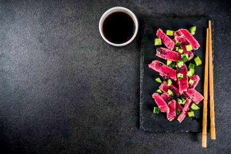 Tuna sashimi poke with raw fresh fish, cucumber, black sesame seeds and soy sauce, black stone...