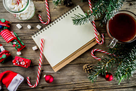 Christmas concept, preparation for xmas holidays, notepad for wish list, santa letter. to do list, with hot hot chocolate cup, Christmas tree decor, fir branches. Old wooden table copy space top viewの写真素材