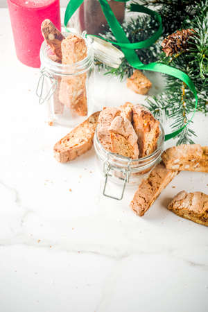 Traditional Christmas pastries, Italian homemade double-baked biscotti or cantuccini cake, with nuts and dried fruits. with xmas decorations and fir branches, white marble background copy spaceの写真素材