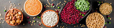 Various assortment of legumes - beans, soy beans, chickpeas, lentils, green peas. Healthy eating concept. Vegetable proteins. Dark concrete background copy space top view banner formatの写真素材