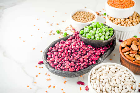 Various assortment of legumes - beans, soy beans, chickpeas, lentils, green peas. Healthy eating concept. Vegetable proteins. White marble background copy space top viewの写真素材