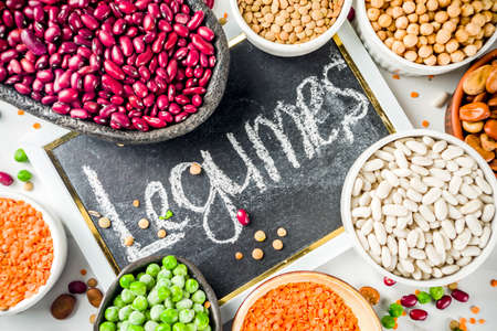 Various assortment of legumes - beans, soy beans, chickpeas, lentils, green peas. Healthy eating concept. Vegetable proteins. White marble background copy space top viewの写真素材