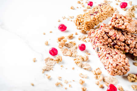 Multi grain granola muesli bar. Healthy sweet food, diet snack, with dried berries, nuts, cereals and honey. On a white marble background, top view copy place for text.の写真素材