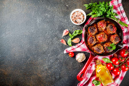 Homemade baked meatballs with tomato sauce in small frying pan on dark rusty stone table. Top view  copy spaceの写真素材