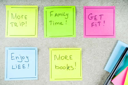 New years resolutions, colorful sticky notes with popular new year resolutions, wooden background...