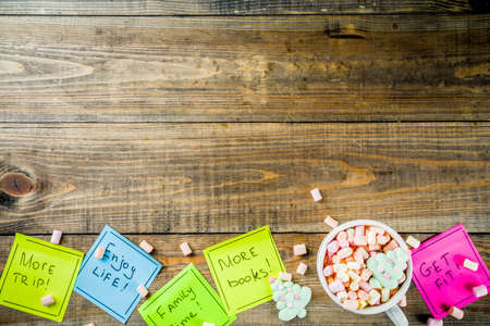 New years resolutions, colorful sticky notes with popular new year resolutions, wooden background with funny hot chocolate cup,  copy space top view flatlayの写真素材
