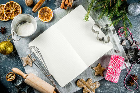 Empty cookbook for Christmas recipes, on dark blue concrete background with ingredients for...