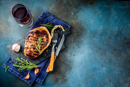 Sliced grilled roast beef with fork for meat and wine on wooden cutting board. Dark blue background. Top view copy spaceの写真素材