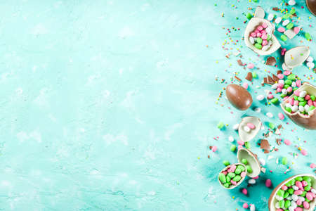 Colorful spring easter sweets background, with chocolate eggs, sugar sprinkles and marshmallow...