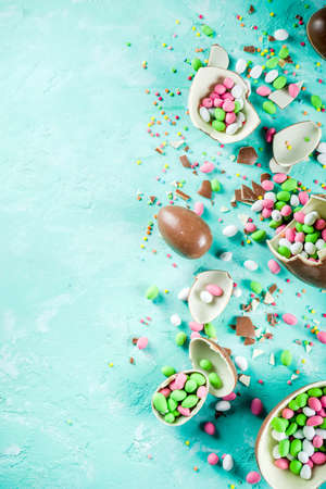 Colorful spring easter sweets background, with chocolate eggs, sugar sprinkles and marshmallow...