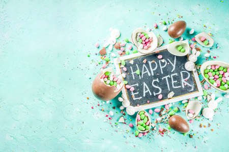 Colorful spring easter sweets background, with chocolate eggs, sugar sprinkles and marshmallow...