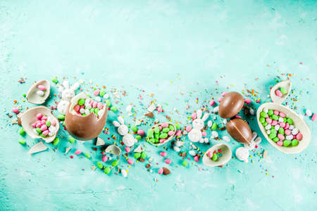 Colorful spring easter sweets background, with chocolate eggs, sugar sprinkles and marshmallow...