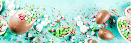 Colorful spring easter sweets background, with chocolate eggs, sugar sprinkles and marshmallow...