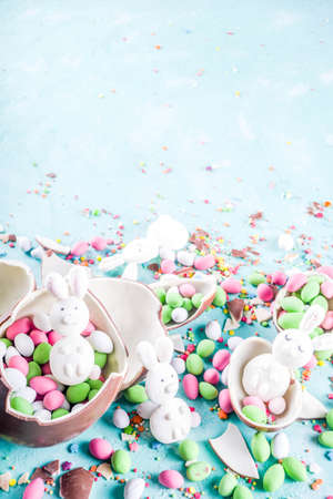 Colorful spring easter sweets background, with chocolate eggs, sugar sprinkles and marshmallow...