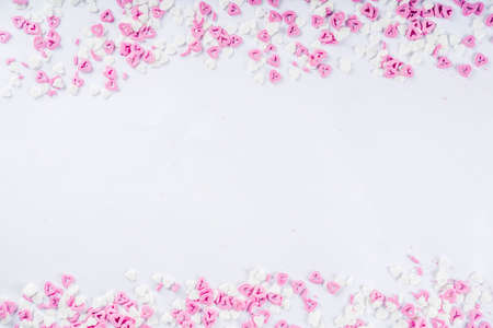 Valentine's sweets background, white background with sugar hearts sweet sprinkles, copy space top...