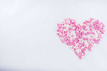 Valentine's sweets background, white background with sugar hearts sweet sprinkles, copy space top view, layout on whiteの写真素材