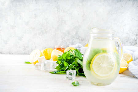 Homemade sour cocktail lemonade, with fresh lemons, mint and honey, white wooden background copy spaceの写真素材