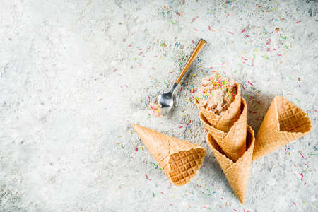 Edible Raw Cookie Dough, sweet modern dessert, with waffle ice cream cones on grey stone background,...