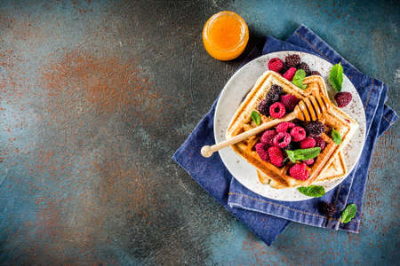 Homemade belgian waffles with berries and honey, on dark blue background copy spaceの写真素材
