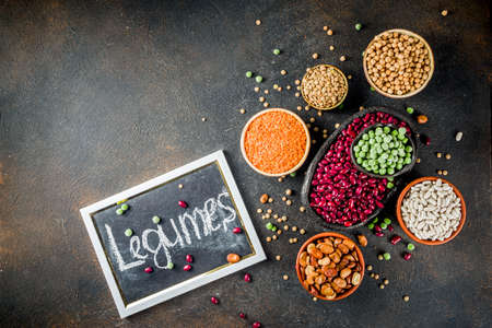 Various assortment of legumes - beans, soy beans, chickpeas, lentils, green peas. Healthy eating concept. Vegetable proteins. Dark concrete background copy space top viewの写真素材