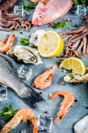 Fresh raw seafood squid shrimp oyster mussels fish with spices of herbs lemon on a light blue background copy space top viewの写真素材