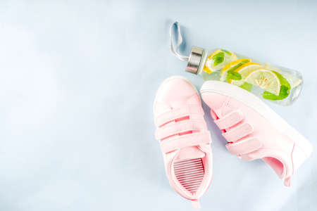 Sport and fitness creative layout, dumbbells, women's sneakers, jump rope, notebook, bottle with detox water with lemon and mint, bright trendy background, top view,  creative layout copy spaceの写真素材