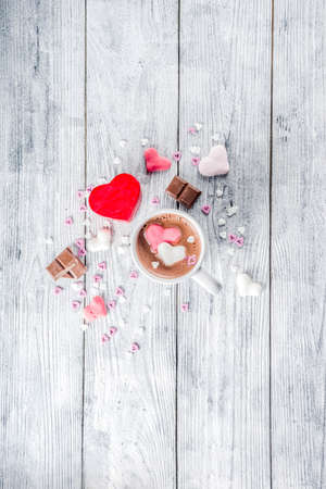 Valentines day treat ideas, two cups hot chocolate drink with marshmallow hearts red pink white color with chocolate pieces, sugar sprinkles, old wooden background copy space top viewの写真素材