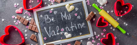 Valentine day baking concept, sweets and baking cooking background for Valentine`s day, with rolling pin, cookie cutters, sugar sprinkling, chocolate. Black concrete table top view copy space bannerの写真素材