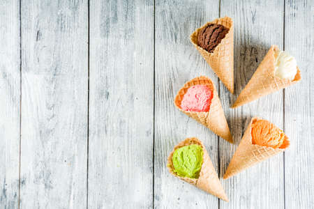Colorful ice cream in waffle ice cream cones, sweet homemade summer dessert, old wooden background...