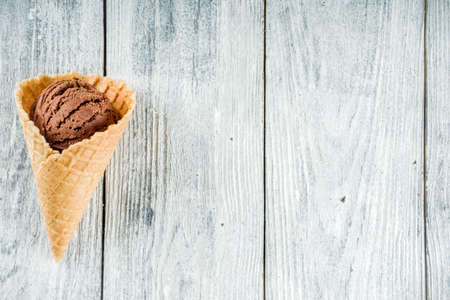 Colorful ice cream in waffle ice cream cones, sweet homemade summer dessert, old wooden background...