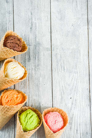 Colorful ice cream in waffle ice cream cones, sweet homemade summer dessert, old wooden background copy space top viewの写真素材