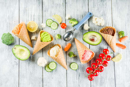 Trendy vegan food, summer healthy dessert concept, colorful diet vegetable ice cream with avocado, cucumber, tomato, beet, carrot, broccoli, cauliflower. Frozen veggie smoothie, wooden backgroundの写真素材