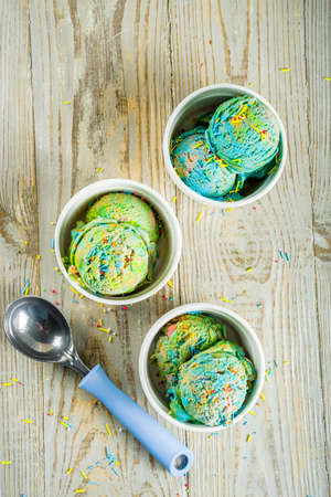 Multicolored rainbow ice cream with icecream cones on wooden background