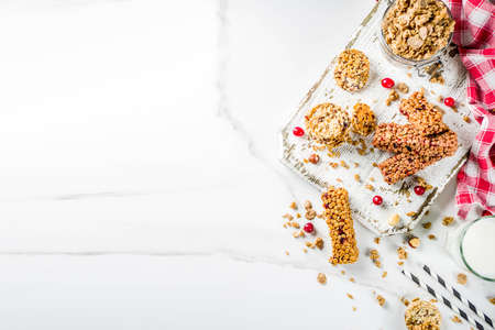 Multi grain granola muesli bar. Healthy sweet food, diet snack, with dried berries, nuts, cereals and honey. On a white marble background, top view copy place for text.の写真素材