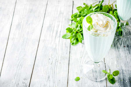 Summer refreshing cocktail, shamrock mint shake, sweet milk drink with fresh mint leaves, wooden background copy spaceの写真素材